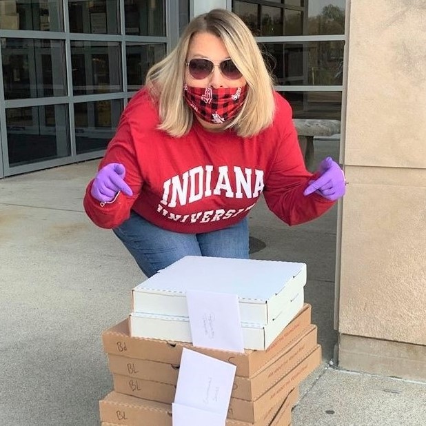 Woman standing and pointing at several pizza boxes